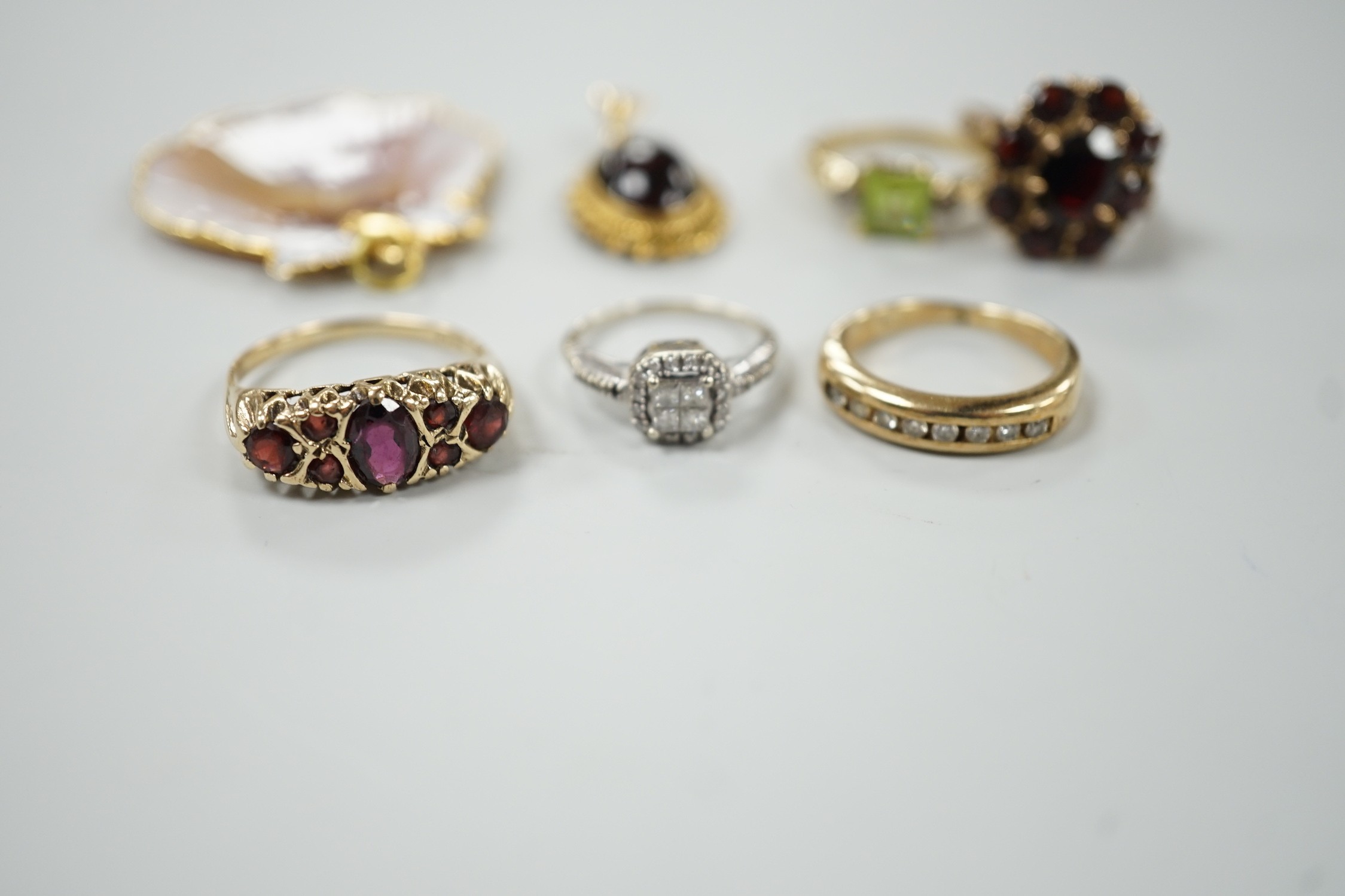 A 9ct and garner cluster set dress ring, size M, gross 4.9 grams, two yellow or white metal and diamond set rings, including half eternity and a yellow metal and garnet set half hoop ring, gross 8.8 grams, a 14k, single